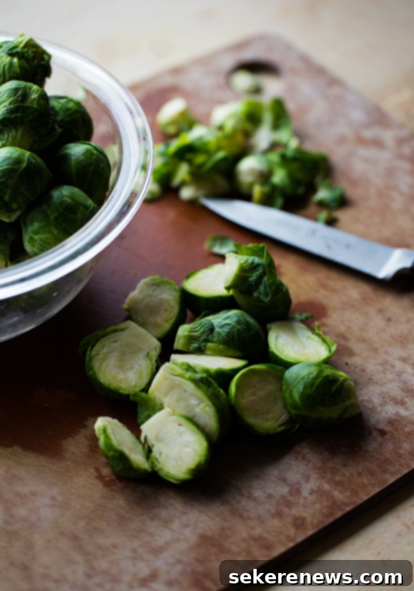 Roasted Brussels Sprouts and Squash with Dried Cranberries and Dijon Vinaigrette. This colorful Thanksgiving side dish recipe is easy and loved by all! #thanksgiving #vegetarian #sidedish #fall #holiday #recipe #abeautifulplate #squash #brusselssprouts Sliced Brussels sprouts on Cutting Board, ready for roasting