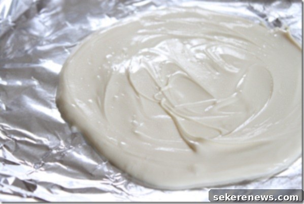Festive Homemade Peppermint Bark 4 Melted dark chocolate spread evenly on foil for peppermint bark.