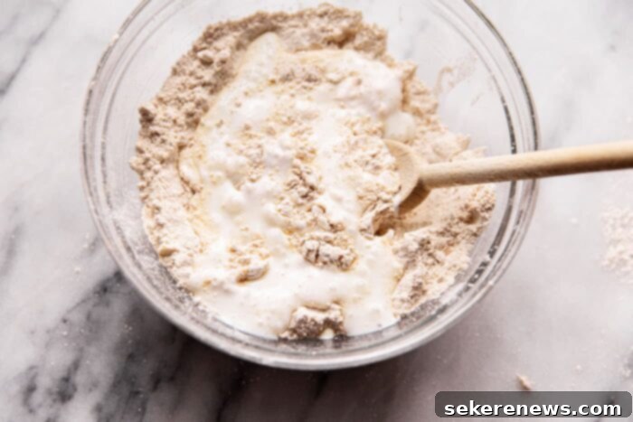 Effortless Whole Wheat Biscuits 8 Pouring buttermilk into biscuit dough mixture