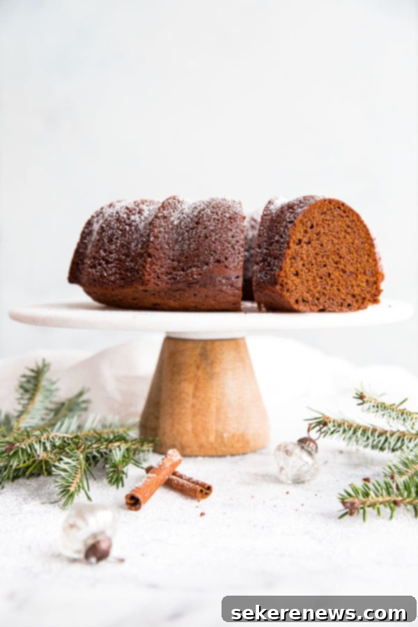 Holiday Gingerbread Bundt with Velvety Eggnog Cream 7 A festive individual serving of Gingerbread Bundt Cake adorned with Eggnog Whipped Cream, garnished with fresh nutmeg, on a white plate.