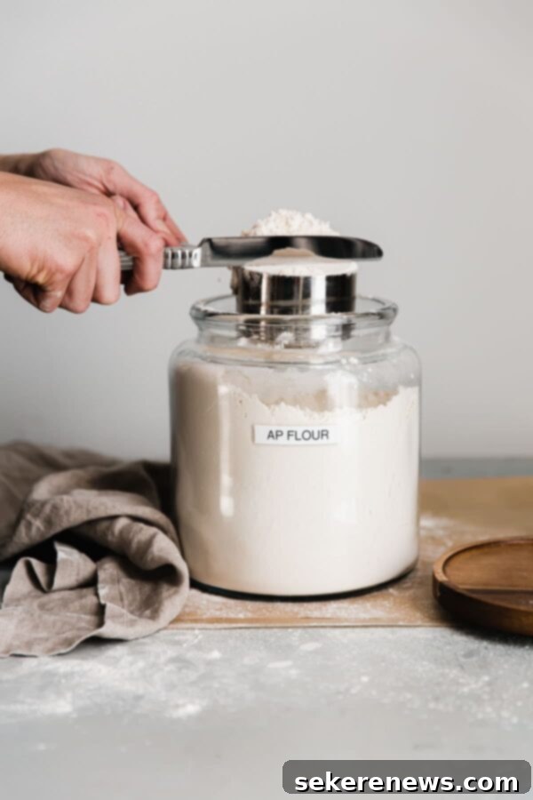 Mastering Flour Measurement 5 A knife leveling off excess flour from a measuring cup, demonstrating the final step for accurate volume measurement.