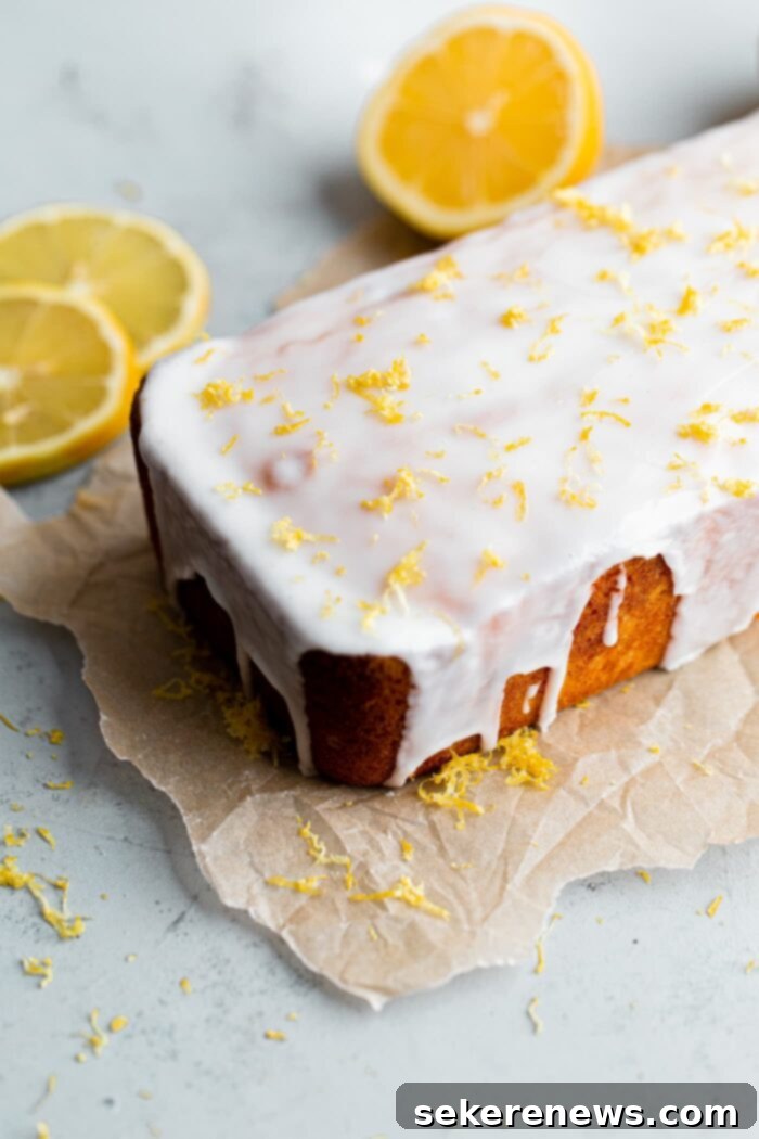 Zesty Lemon Pound Cake 3 A close-up shot of a whole lemon loaf cake, generously drizzled with a thick, tart lemon glaze, showcasing its inviting texture and golden-brown crust before being cut.