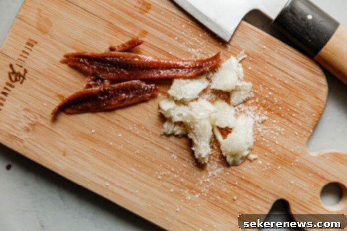 Caesar Salad Dressing Two Ways 13 Anchovy Fillets and Smashed Garlic on Cutting Board