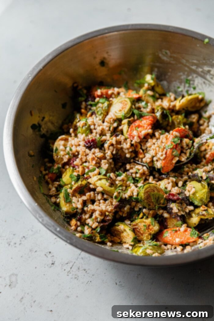 Hearty Autumn Farro Salad 11 Fall Farro Salad with Maple Tahini Dressing mixed in, served in a large mixing bowl with various toppings.