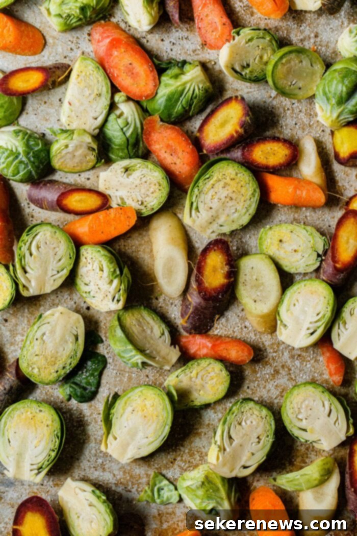 Hearty Autumn Farro Salad 6 Prepped Brussels sprout halves and sliced tri-color carrots laid out on a sheet pan, drizzled with olive oil, salt, and pepper.